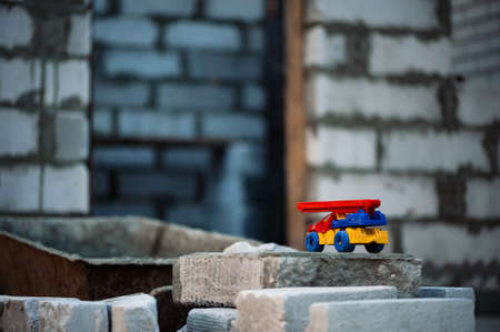 Small toy truck with crane stands on foam block on construction background.の写真素材