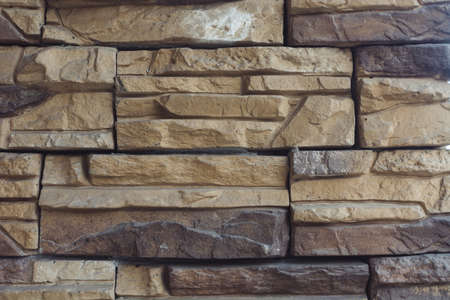 Unusual designer brick wall of cream color made of bricks of different shapes and shades. Background image of beautiful interior wall. Exterior from varicolored stones.の写真素材