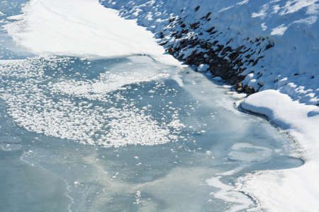 Beautiful snowy landscape with river is covered ice. Frozen river during thaw.
