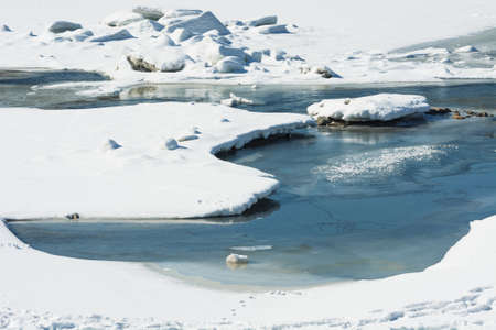 Beautiful snowy landscape with river is covered ice. Frozen river during thaw.の写真素材