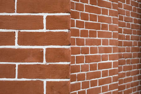 Red brick wall in perspective. Edge of brick wall. Geometric background image from angle of brown...