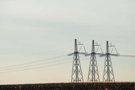 Power lines on background of blue sky close-up. Silhouette of electric pole with copy space. Wires of high voltage above ground. Electricity industry.の写真素材