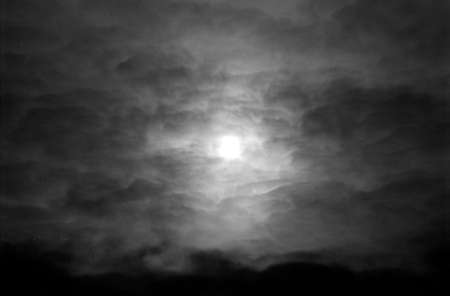 Dramatic cloudy sky in grayscale on film. Overcast weather and sun through cumulus clouds. Monochrome atmospheric dark scanned analog photography with grain and scratch. Lomography of nature.の写真素材