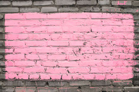 Old realistic dirty brick wall made of pink brick. Uneven brickwork. Center of wall is painted pink. Big rectangle for mock up in center of shot close-up.の写真素材