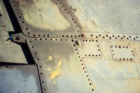 Fragment of metal fuselage of old airplane with rusty bolts and scratches. Vintage background of surface of plane close up. Textured side of retro technology.の写真素材