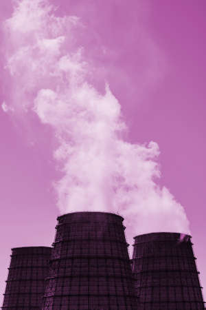 Three big tower of CHPP close-up. Steam from wide pipe of CHP on sky. Industrial background of TPP in pink tones with copy space. Huge pipes of thermal power plant produce steam for electric power.の写真素材