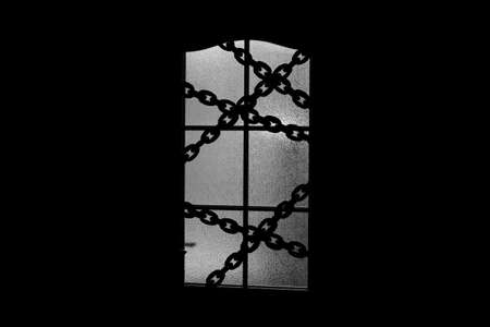 Dark silhouette of glass door with chain. Locked on chain alone in room behind door on Halloween....
