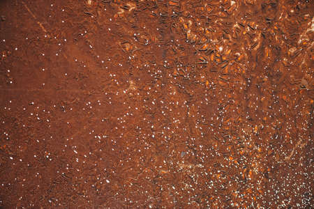 Rough dirty brown wall close-up. Color background with white sprays of dye. Brown orange texture of concrete wall surface with white spots. Painted backdrop. Exfoliated paint. Flaking stucco.の写真素材