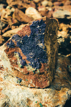 Raw ore on ground close-up. Multicolor rough stone in sunlight. Textured vivid geological background...