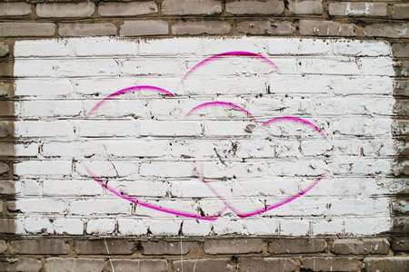 Two drawn hearts on brick wall with white paint close-up. Mock up. Urban background with two painted hearts. Imperfect exterior with love symbol graffiti. Valentine day image. Unideal brickwork.の写真素材