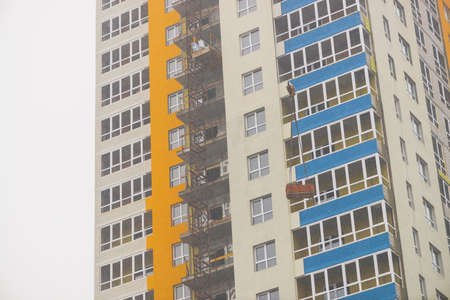 Concept of apartment building under construction close-up. Exterior of multicolor new multi-story...