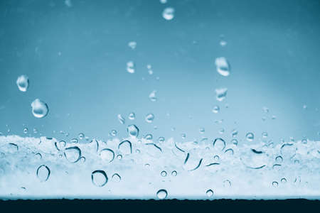 Window glass with frozen drops of rain. Atmospheric mint blue light background with raindrops....