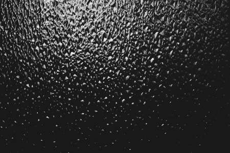 Corrugated window glass with light reflection in night. Atmospheric monochrome dark background....