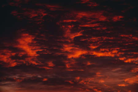 Fiery red blood vampire dawn. Amazing warm dramatic fire cloudy sky. Vivid orange sunlight. Atmospheric background of sunrise in overcast weather. Hard cloudiness. Storm clouds warning. Copy space.の写真素材