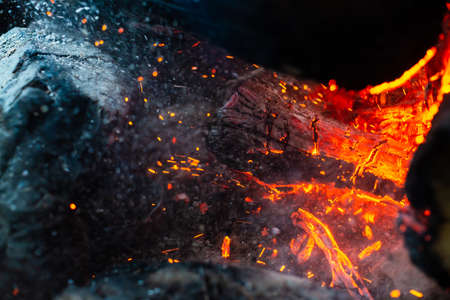 Smoldered logs burned in vivid fire close up. Atmospheric background with flame of campfire....