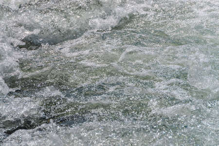 Natural texture of foamed water surface. Rapids of river close-up. Fast flow in mountain creek. Background of clean water waves with copy space. Textured foam of shiny stream. Fast river texture.の写真素材