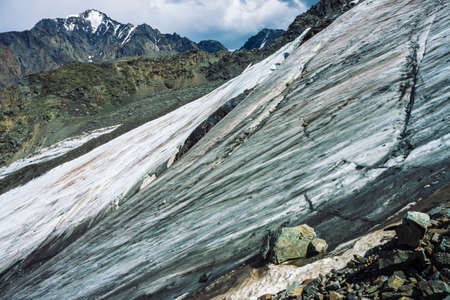 Snow on giant mountain ridge. Wonderful ice terrain on mountainside. Icy steep slope. Amazing snowy rock. Climb high in mountains. Atmospheric minimalist landscape of majestic nature of highlands.の写真素材
