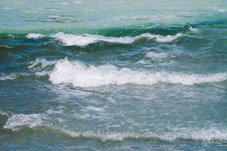 Detailed texture of turquoise rushing water surface. Rapids of mountain river close up. Background of clean water waves.の写真素材