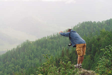 Mad tourist on mountain peak. Joyful traveler dives into abyss under rain. Crazy man is jumping on...