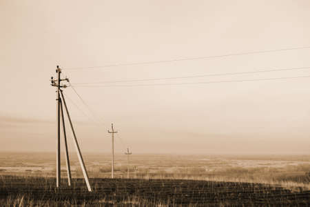 Atmospheric landscape with power lines in field under sky in sepia tones. Background image of...