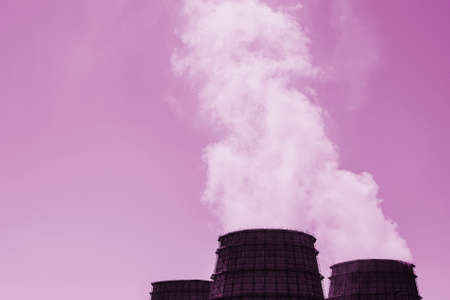 Three big tower of CHPP close-up. Steam from wide pipe of CHP on sky. Industrial background of TPP in pink tones with copy space. Huge pipes of thermal power plant produce steam for electric power.の写真素材