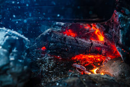 Smoldered logs burned in vivid fire. Atmospheric background with orange flame of campfire. Unimaginable detailed image of bonfire from inside with copy space. Whirlwind of smoke and ash close up.の写真素材