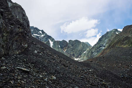 Snow on mountain range. Atmospheric snowy ridge under blue cloudy sky. Wonderful giant rocks. Climb...