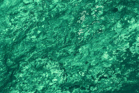 Vintage green background. Rough painted wall of emerald color. Imperfect plane of virid colored. Uneven old decorative toned backdrop of green tint. Texture of emerald hue. Ornamental stony surface.の写真素材