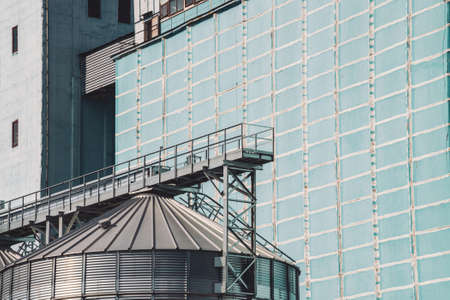 Agricultural silos. Storage and drying of grains, wheat, corn, soy, sunflower. Industrial building exterior. Big metallic silver containers close-up. Background of agricultural tanks with copy space.の写真素材