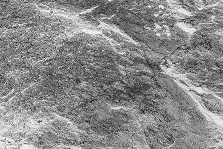 Vintage monochrome background. Rough painted wall of black and white color. Imperfect plane of grayscale. Uneven old decorative backdrop. Texture of black-white. Monochromatic ornamental stony surfaceの写真素材