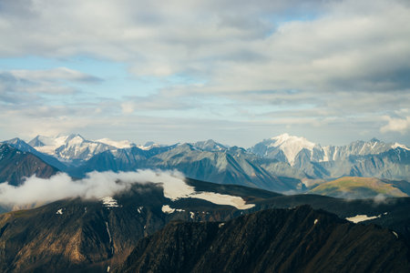 Atmospheric alpine landscape with big gold shiny snowy rockies and giant glacier in golden hour. Low...