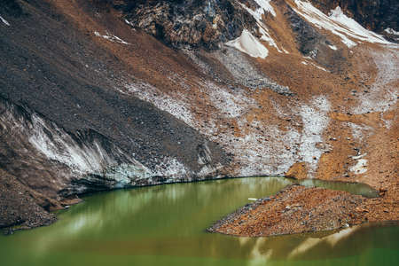 Stones on slope of glacier above mountain lake of acid green color. Beautiful emerald glacial lake...