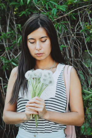Inspired girl with lush dandelion bouquet in garden among summer greenery. Country girl with...