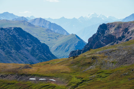 Awesome alpine landscape with great snowy mountain behind rocky mountains and deep gorge. Giant rockies and deep abyss. Wonderful highland scenery with huge glacier and big rocks and precipice.の写真素材