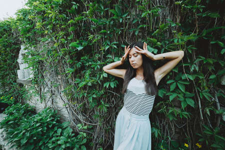 Crazy inspired girl in garden among summer greenery. Mad attractive girl near green hedge in spring...