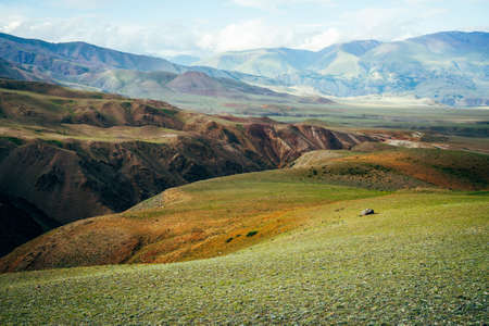 Awesome vivid mountain landscape with deep gorge. Multicolor mountains, green pass and ravine in sunlight. Picturesque sunny scenery with beautiful hills and rocks. Colorful view to unusual relief.の写真素材