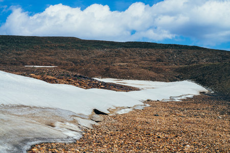 Firn on stony hill in highlands close-up. Minimal mountain landscape with glacier on hillside...