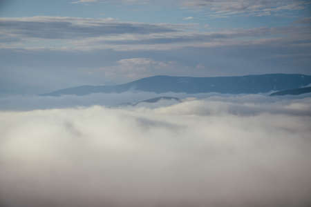 Awesome alpine landscape with snowy mountain range on horizon above clouds. Atmospheric minimal...