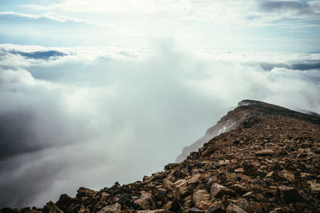 Atmospheric highlands scenery on top of mountain ridge above thick low clouds. Minimalist view from precipice edge over clouds. Beautiful minimal alpine landscape with mountain range over dense cloudsの写真素材