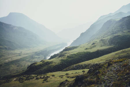 Misty mountain landscape with hills and rocks on background of wide mountain river in mist....