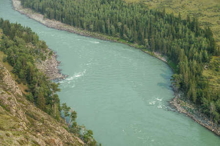 Beautiful aerial view from above to wide mountain river. Scenic view from top to big turquoise river in mountains. Vivid sunny landscape with wide turquoise river and green hills and rocks with trees.の写真素材