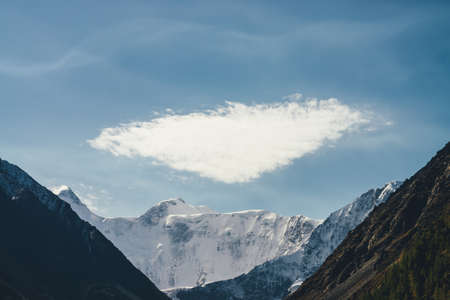 Minimalist alpine landscape with high snow-covered mountain with snowy peaked top under cirrus...