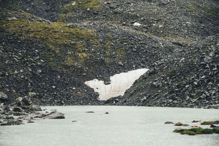 Bleak rainy landscape with rain circles on water surface of mountain lake. Atmospheric mountain...