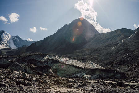 Scenic highlands landscape with big cracked glacier with scratches among moraines on background of...
