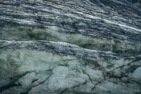 Minimalist nature background of glacier surface with cracks and scratches. Minimal natural backdrop of icy wall and blocks of ice from glacier close up. Beautiful nature texture of shiny glacial wall.の写真素材