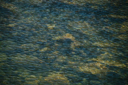 Meditative ripple of mountain lake. Beautiful relaxing background of blue green transparent water of...