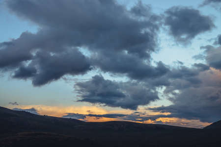 Beautiful mountain scenery with golden dawn light in cloudy sky. Scenic mountain landscape with...