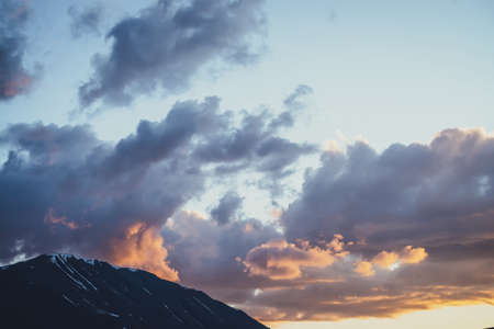 Atmospheric mountain scenery with lilac dawn sky. Scenic landscape with illuminating sunset in mountains. Beautiful sunrise in mountains in pastel tones. Illuminating color in dawn cloudy sky.の写真素材