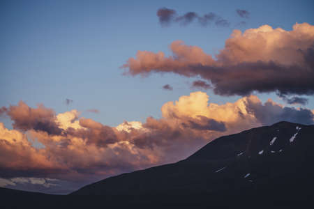 Atmospheric mountain scenery with lilac dawn sky. Scenic landscape with illuminating sunset in mountains. Beautiful sunrise in mountains in pastel tones. Illuminating color in dawn cloudy sky.の写真素材