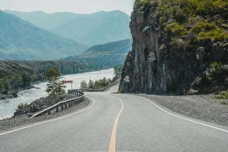 Scenic landscape with speed limit road sign on mountain highway. Beautiful view to tract in highlands. Scenery with asphalt road with road markings. Highway with solid line and mountain river.の写真素材